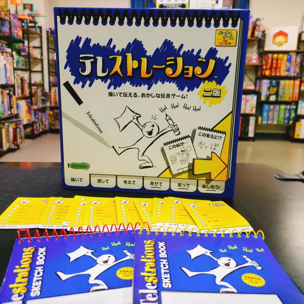 テレストレーションの箱とボードゲーム風景